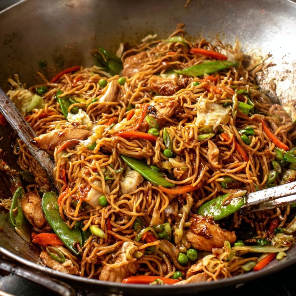 Chicken lo mein stir fry with noodles, vegetables, and tender chicken in a wok.