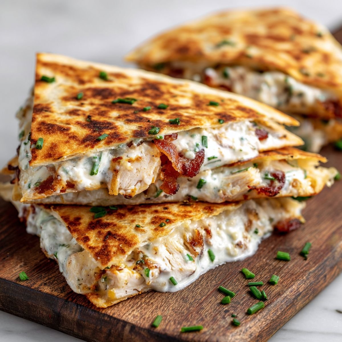 Two chicken bacon ranch quesadilla wedges showing crispy bacon and chicken filling with minimal melted cheese.