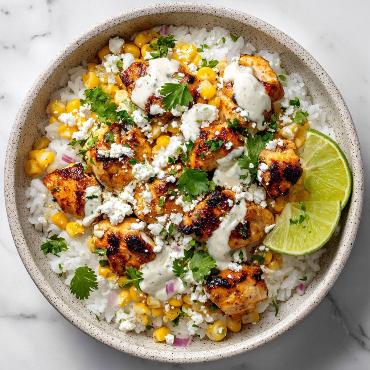 Street corn chicken rice bowl with charred chicken, sweet corn, creamy sauce and fresh cilantro in ceramic bowl