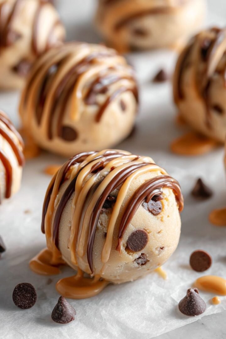 Frozen greek yogurt peanut butter bites with chocolate chips and peanut butter drizzle on parchment. Healthy protein packed no bake frozen treats ready in 15 minutes.