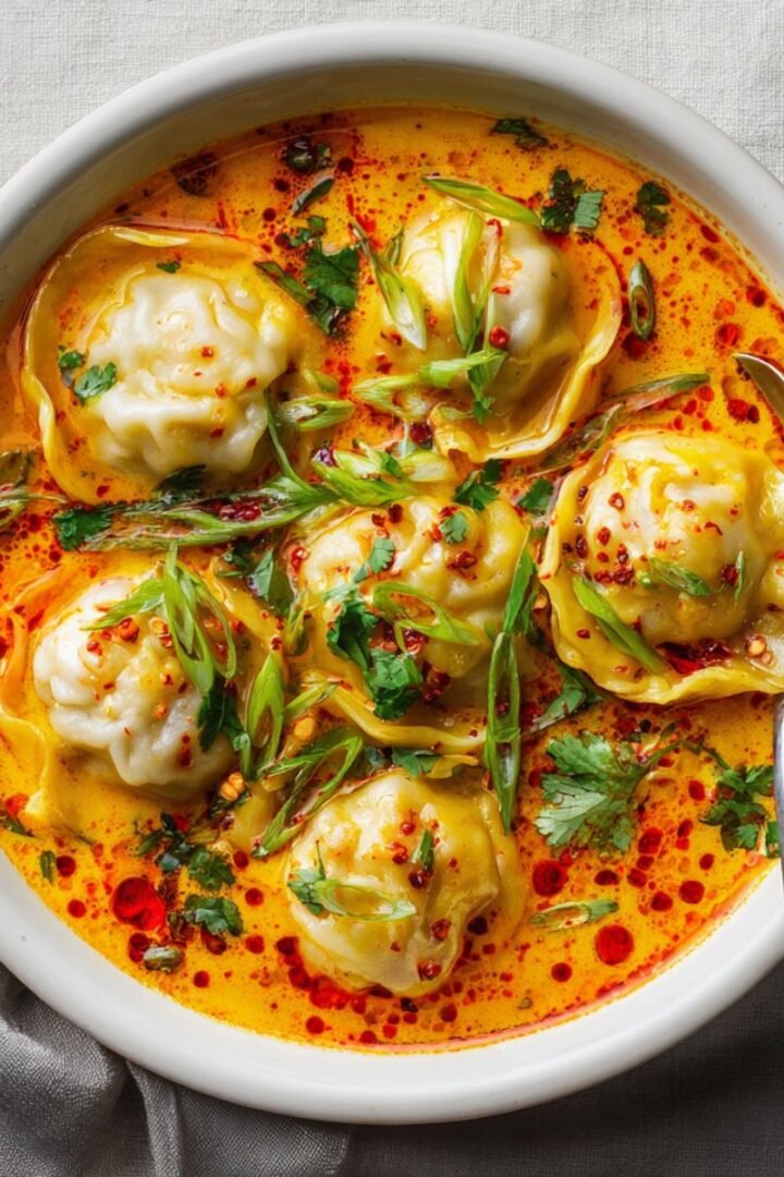 Golden 35 minute coconut curry dumpling soup with pillowy white dumplings floating in vibrant orange coconut curry broth garnished with fresh green onions and chili oil