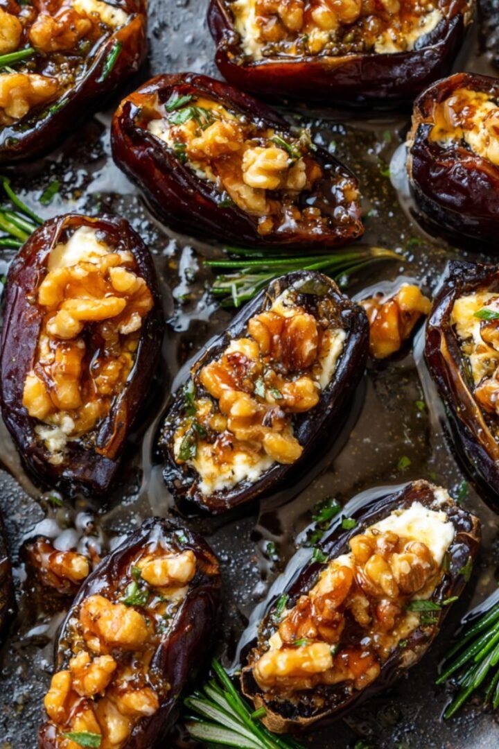 Roasted 25 minute goat cheese stuffed dates with walnuts honey and fresh rosemary on baking sheet