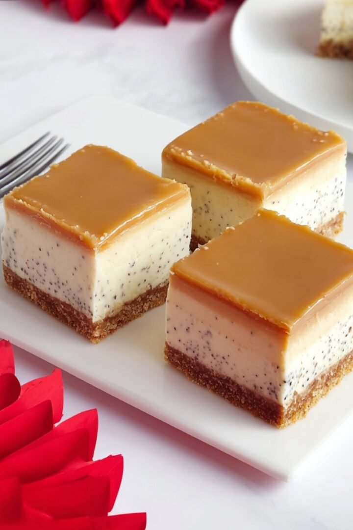No-Bake Earl Grey Mousse Cheesecake bars on a white marble board with a golden biscuit base, speckled Earl Grey mousse layer, and smooth caramel glaze topping.